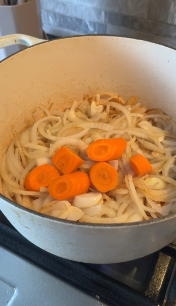 Onions and carrots softening in a Dutch oven