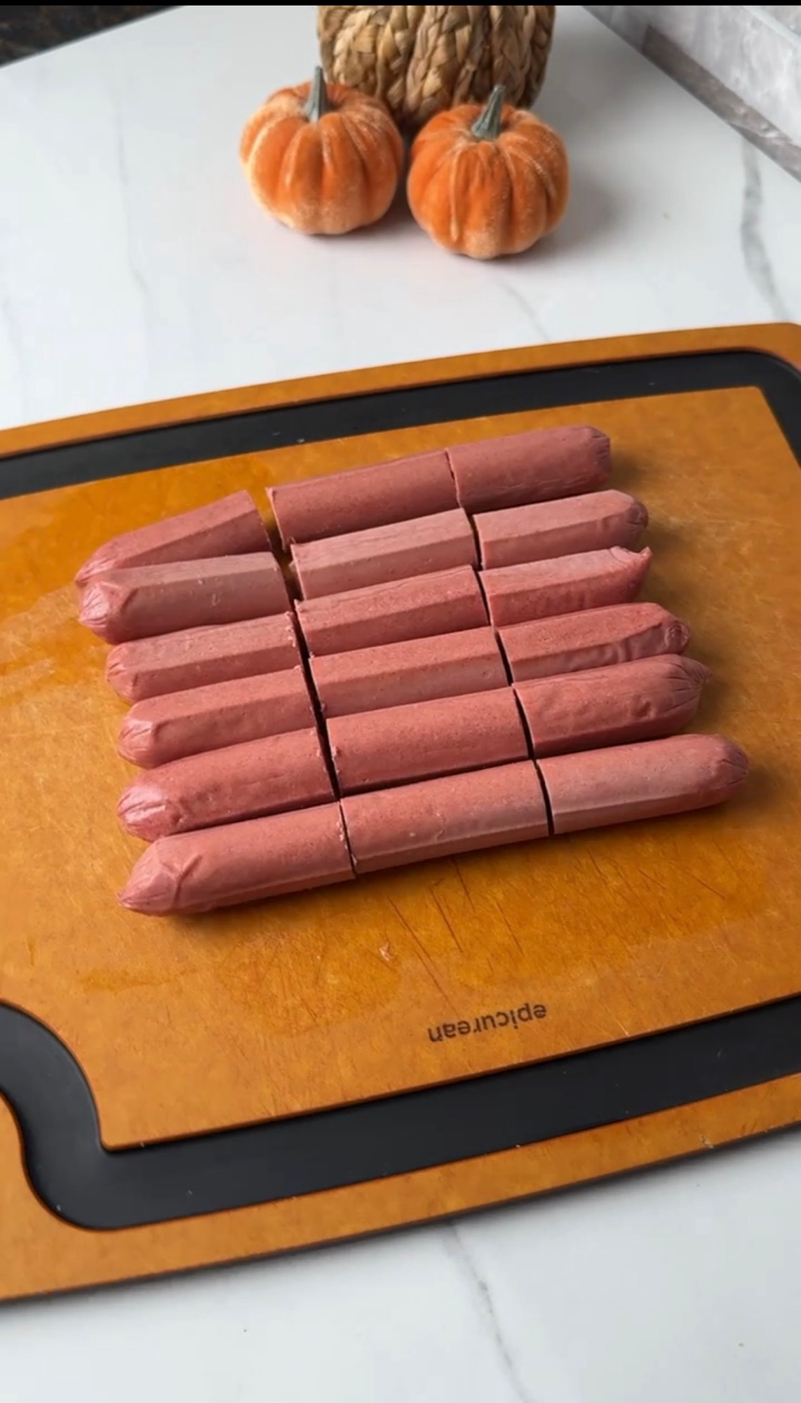 Hot dogs cut into thirds on a cutting board for ghost dogs