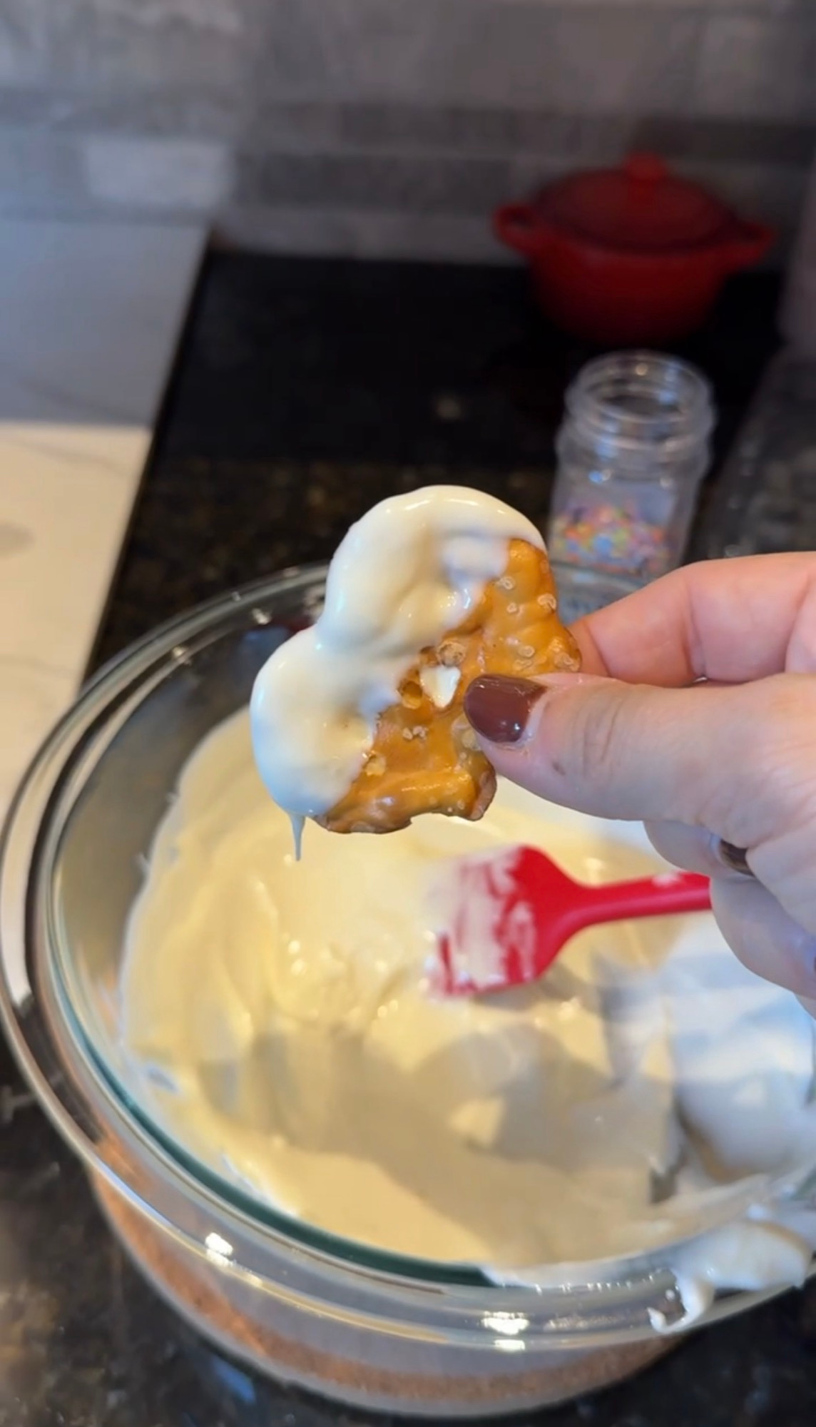 A pretzel being dipped in melted white chocolate