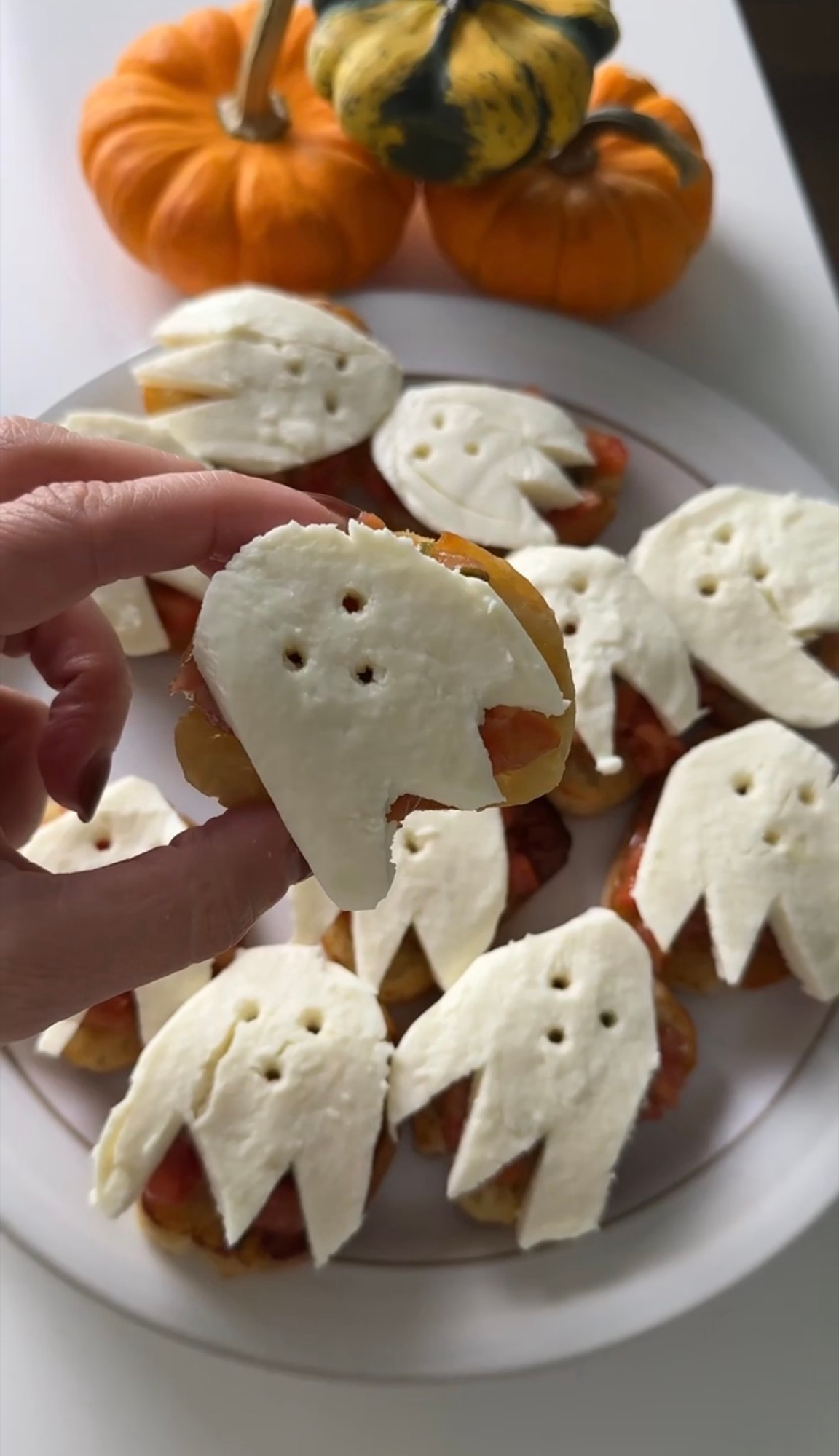 Holding a ghost bruschetta topped with a fresh mozzarella ghost