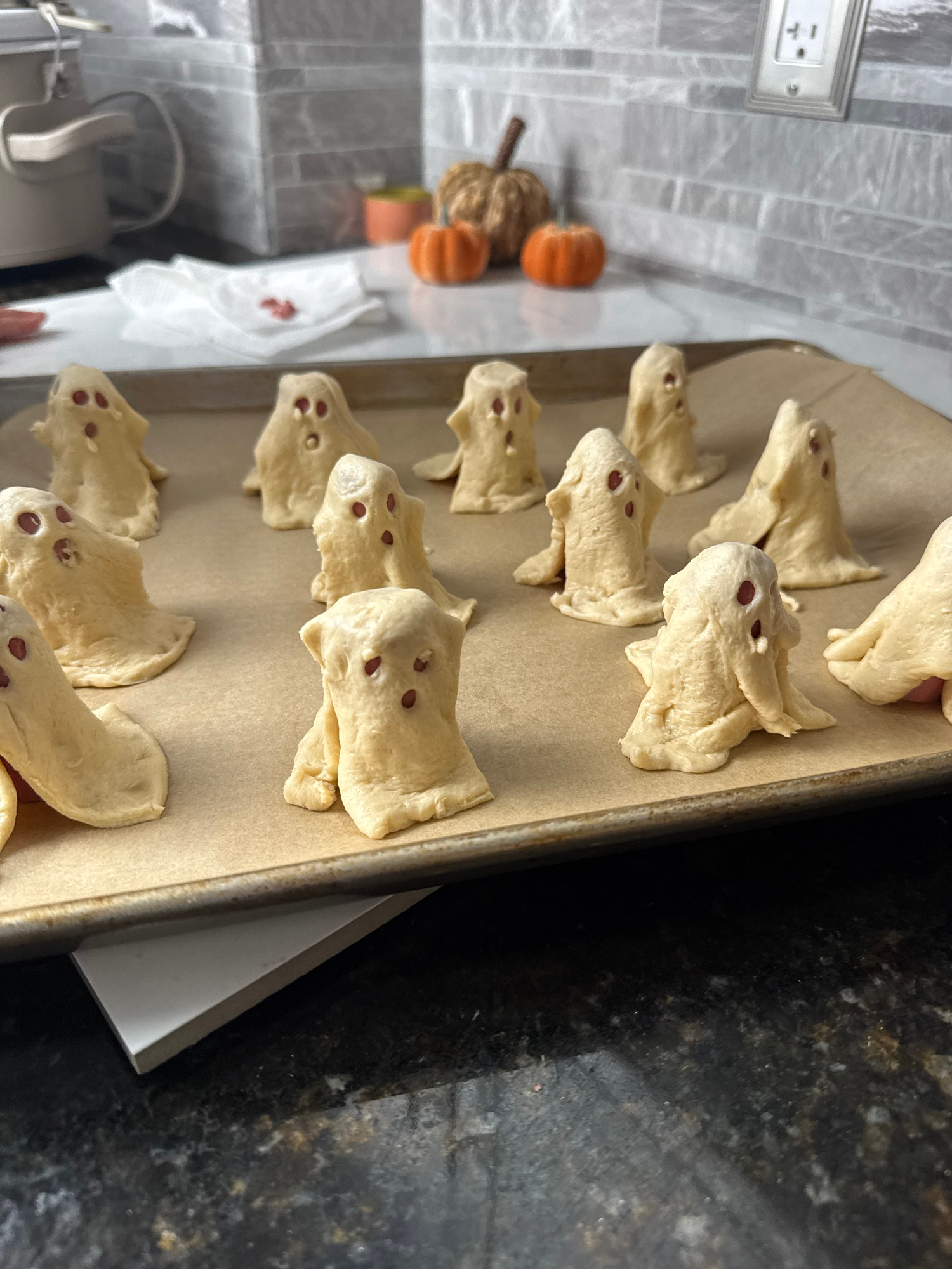 Raw ghost dogs with crescent dough draped over hot dogs before baking