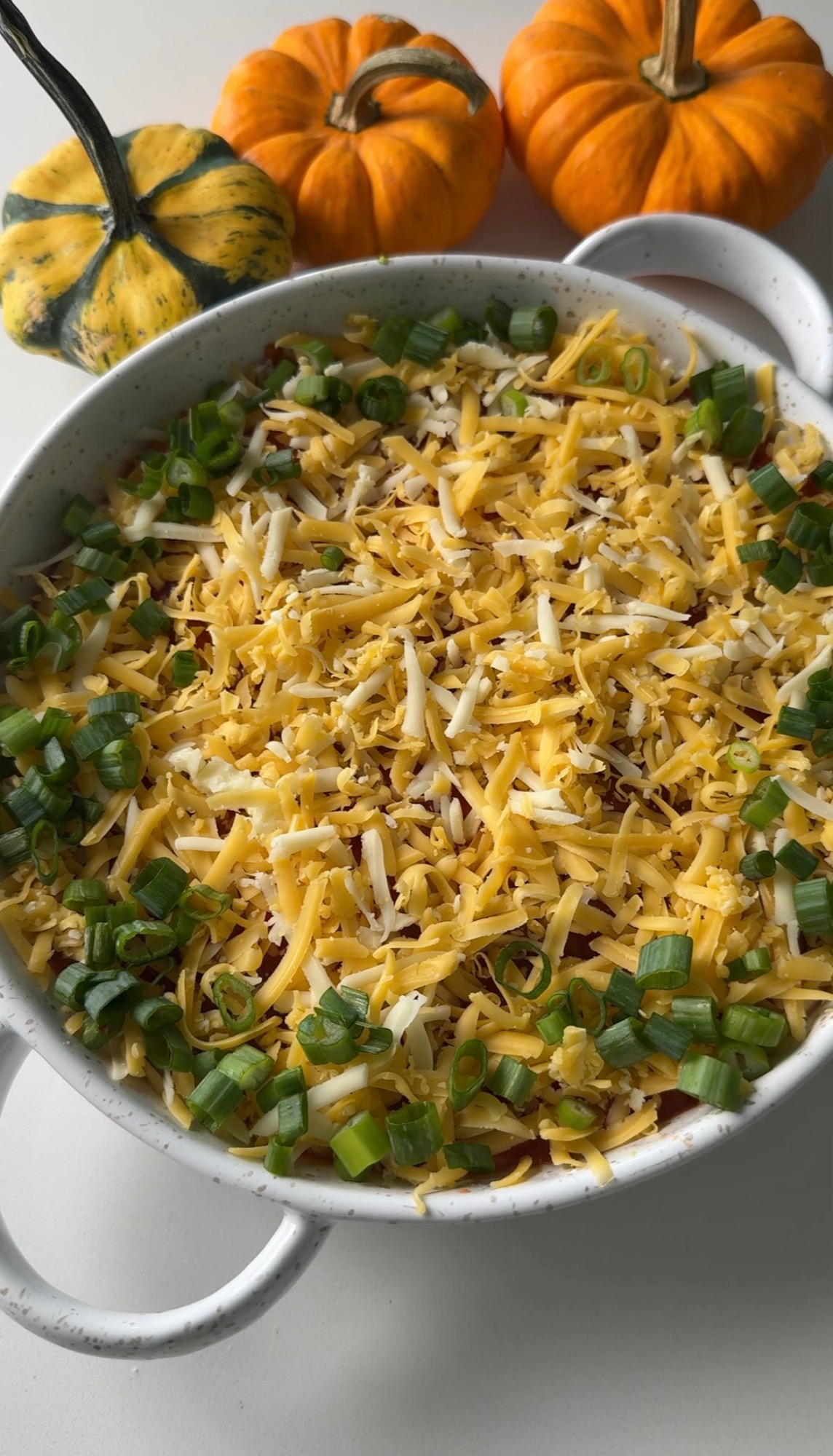 Shredded cheese and green onion topping the layered dip
