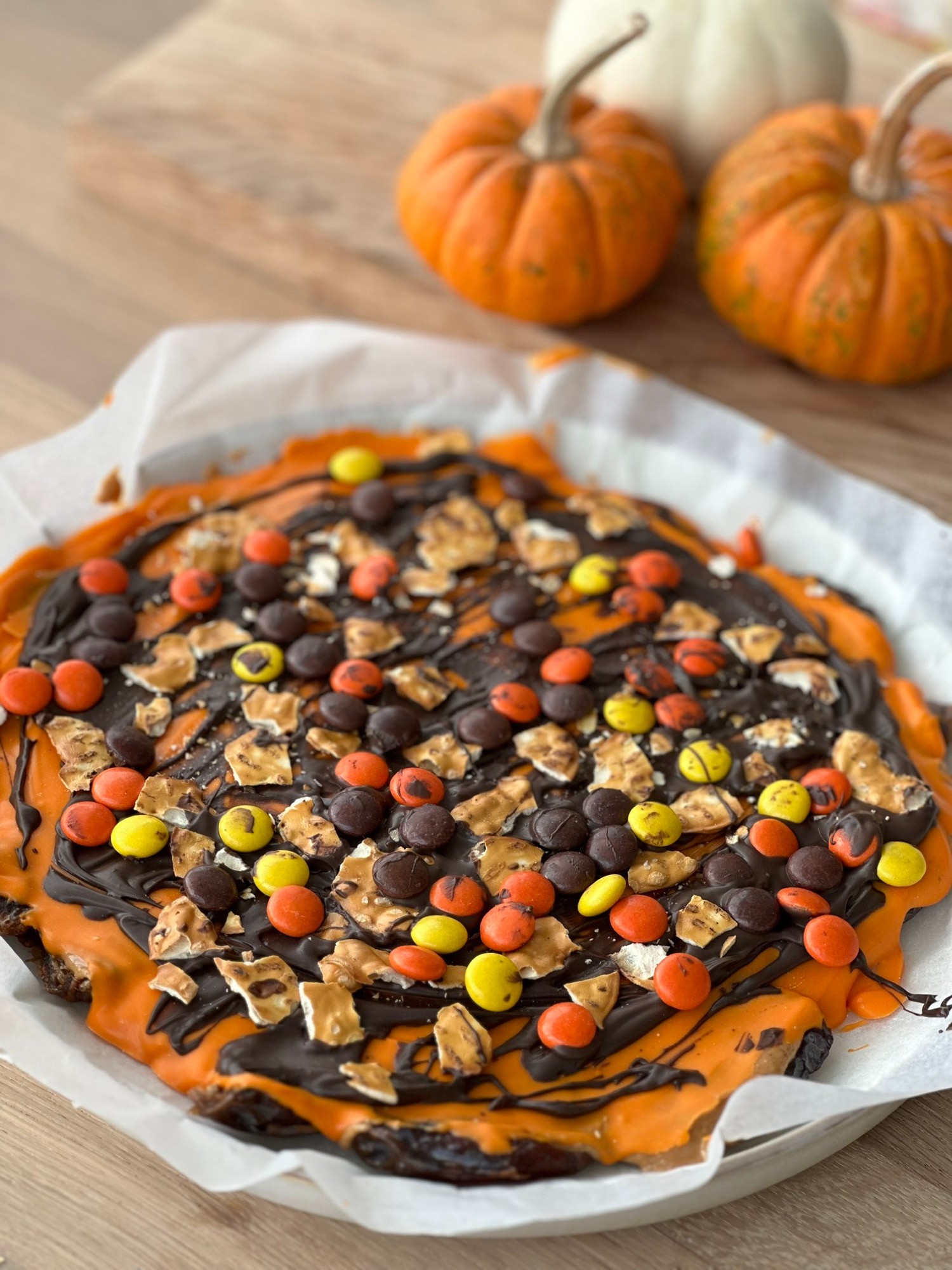 Halloween chocolate peanut butter date bark with festive candy and mini pumpkins