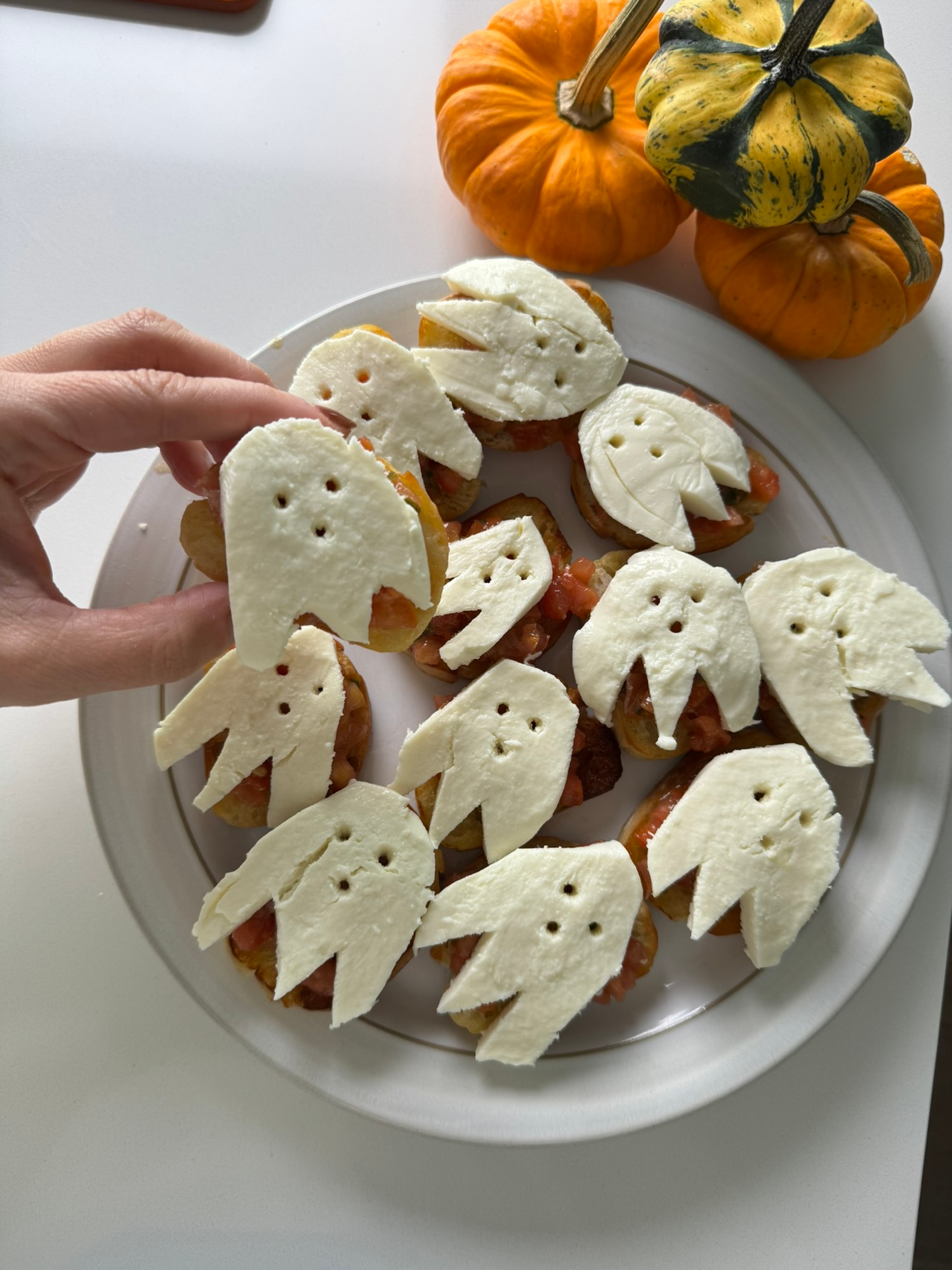 Halloween ghost bruschetta on a plate with fresh mozzarella ghosts and pumpkins