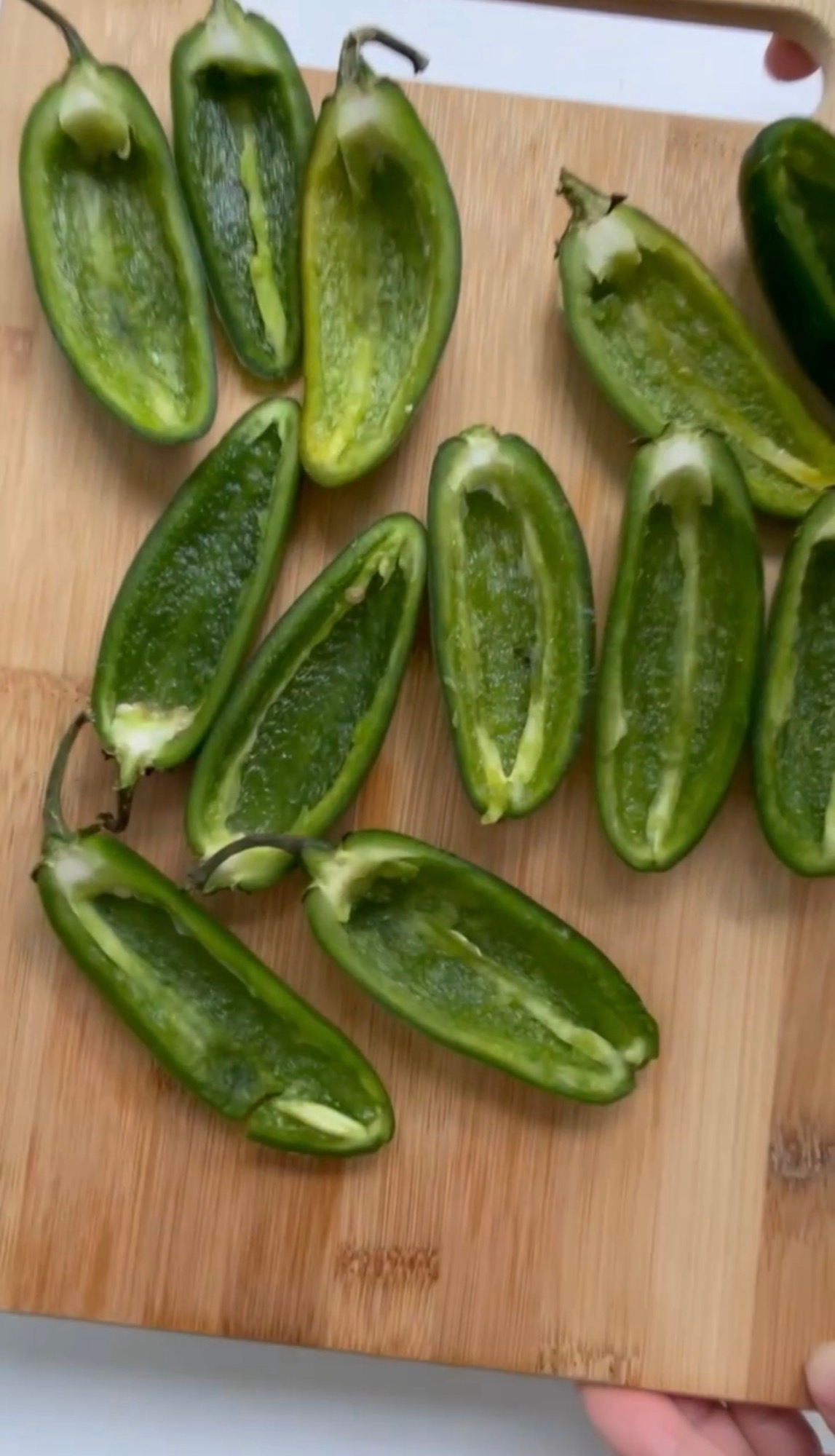 Halved and seeded jalapenos on a cutting board