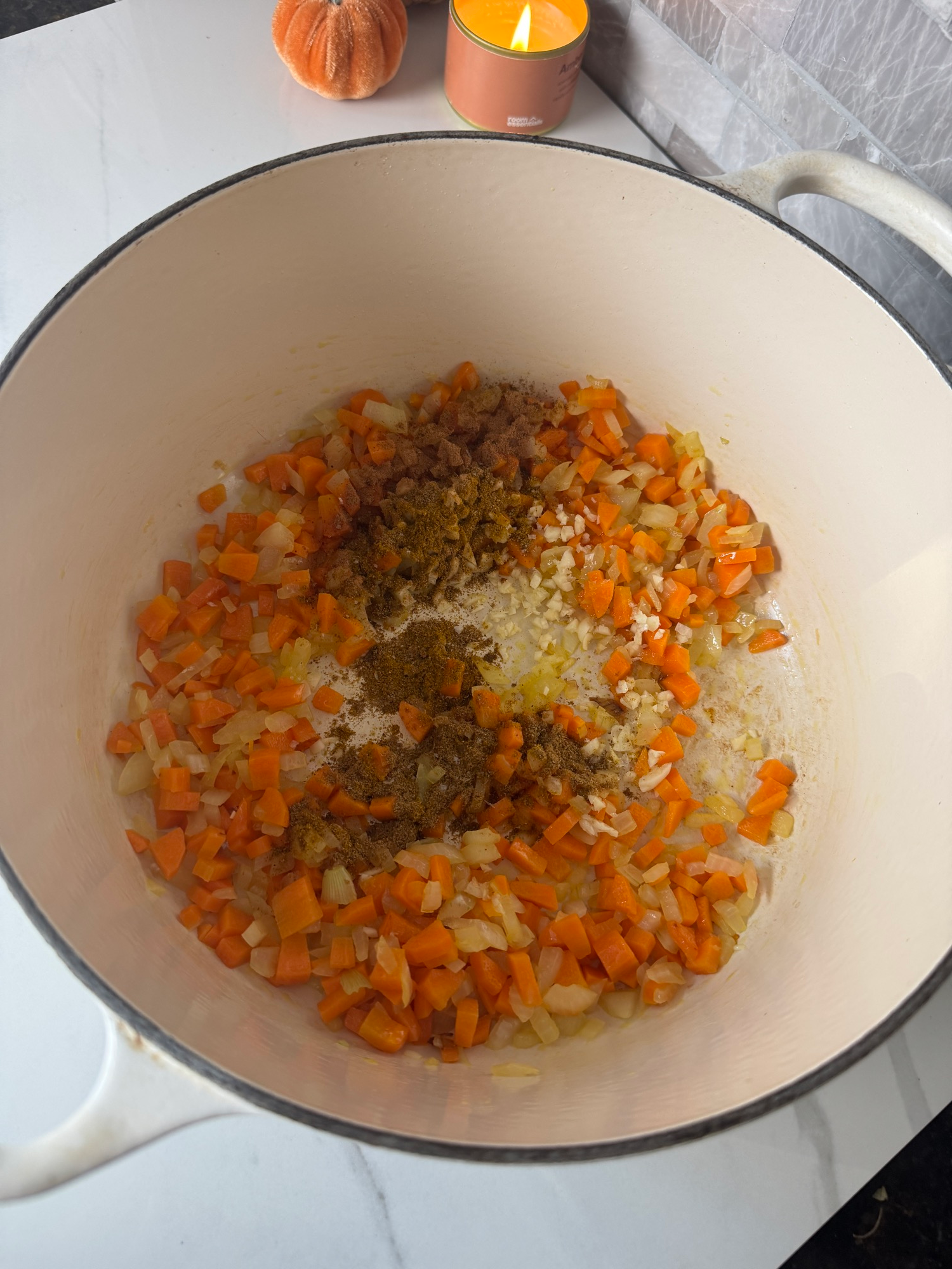 Onion, carrots, garlic, and warm spices cooking in a Dutch oven