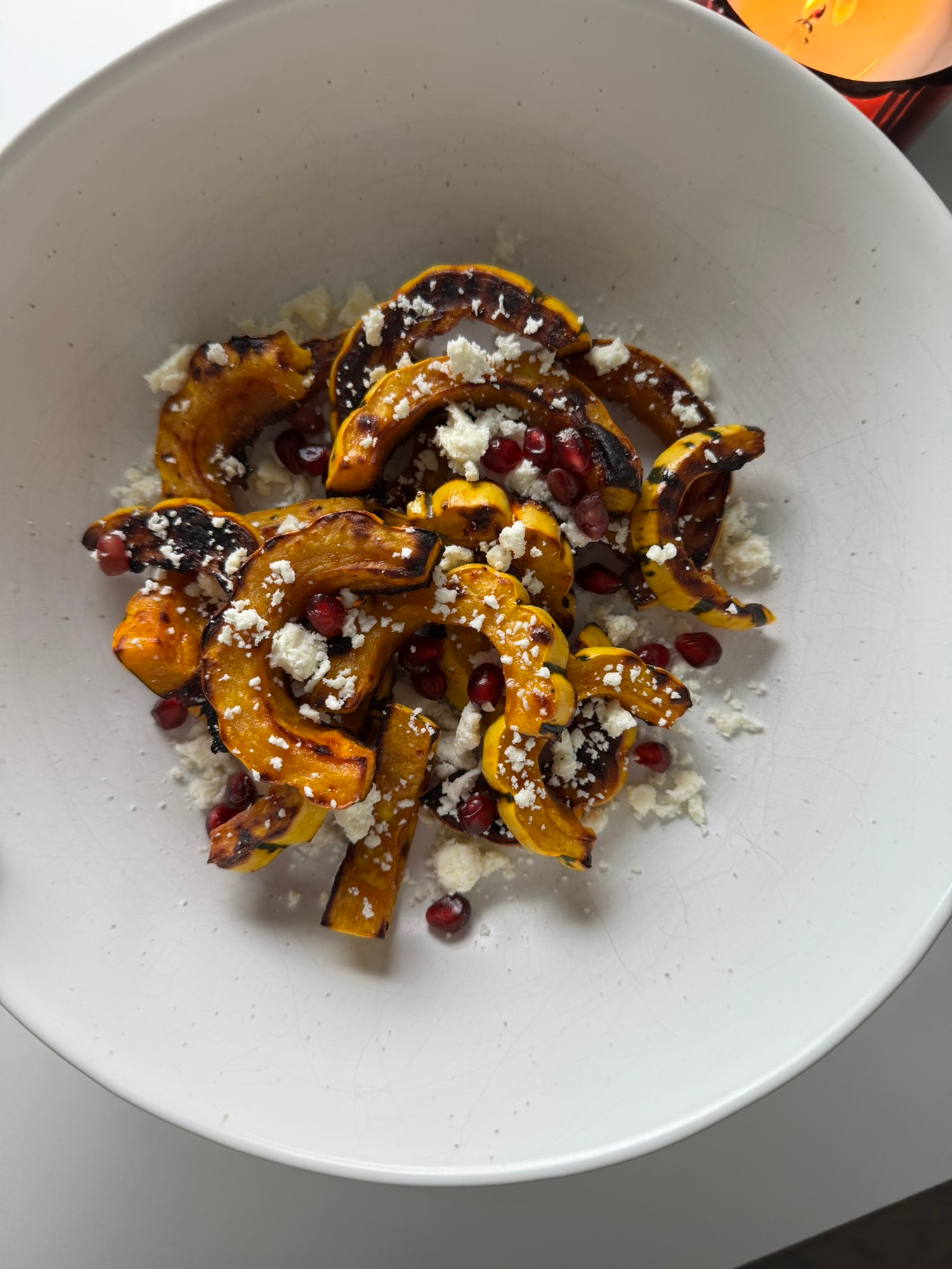 Maple delicata squash with feta and pomegranate seeds served in a bowl