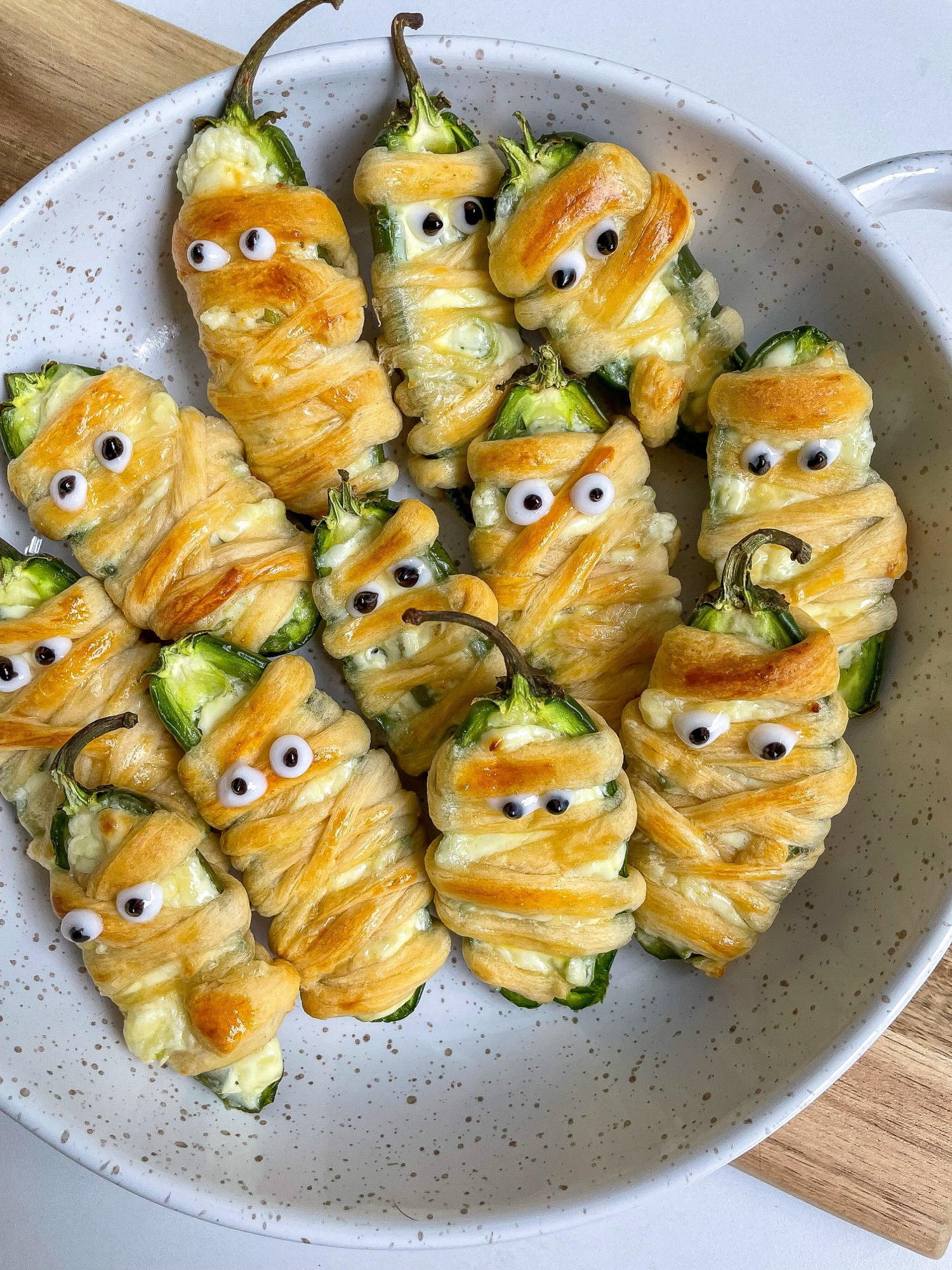 Baked mummy jalapeno poppers wrapped in crescent dough with candy eyes