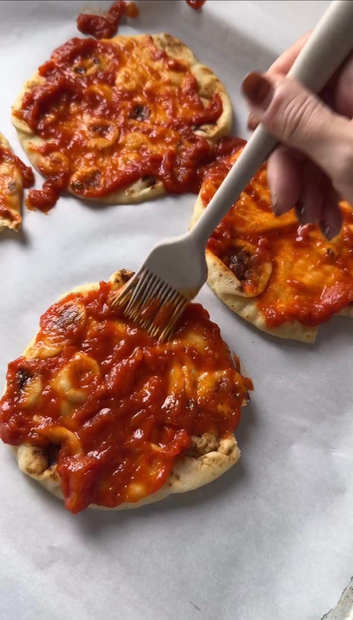 Brushing pasta sauce onto naan for pizza