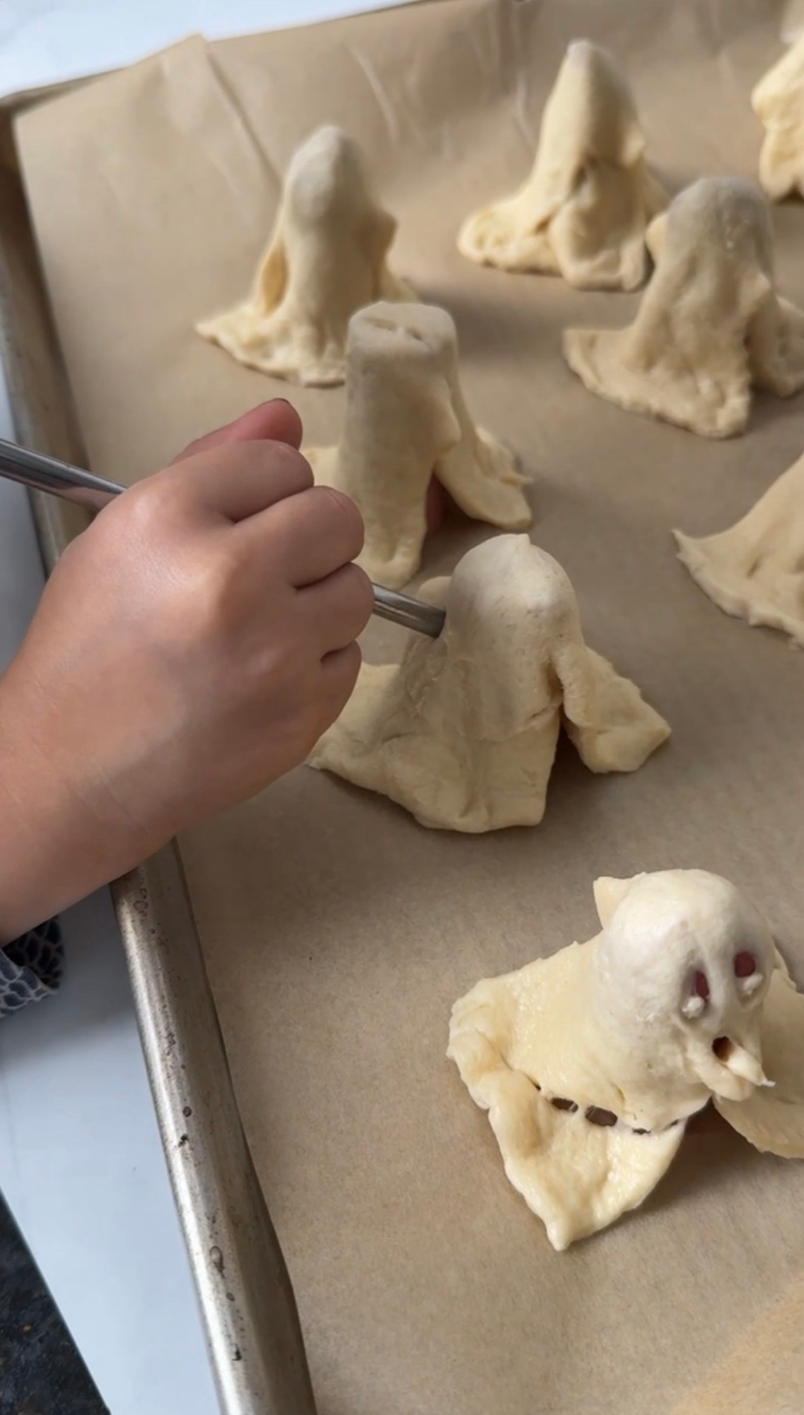 A child poking ghost faces into the dough with a straw