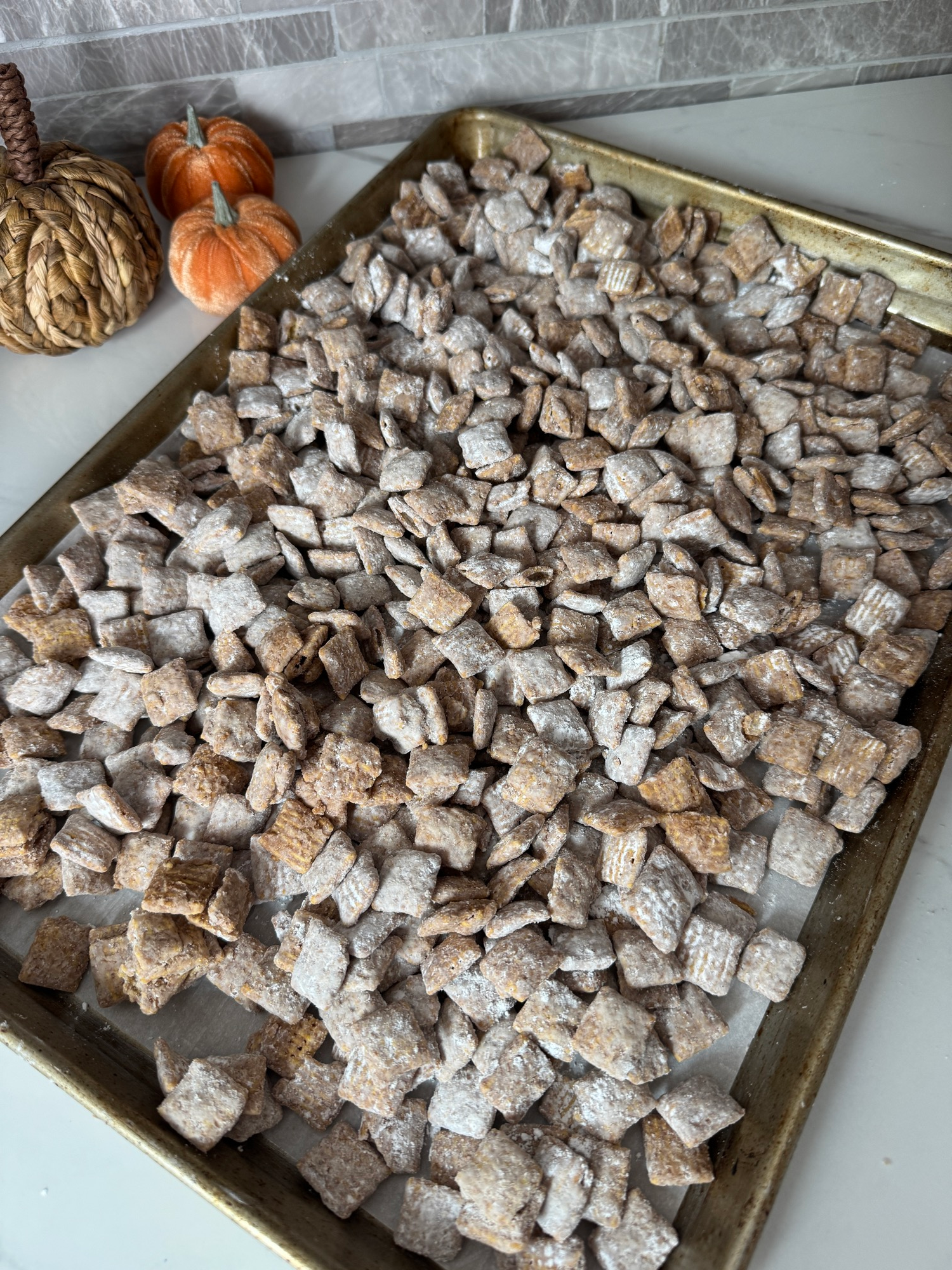 Powdered sugar coated puppy chow spread on a baking sheet