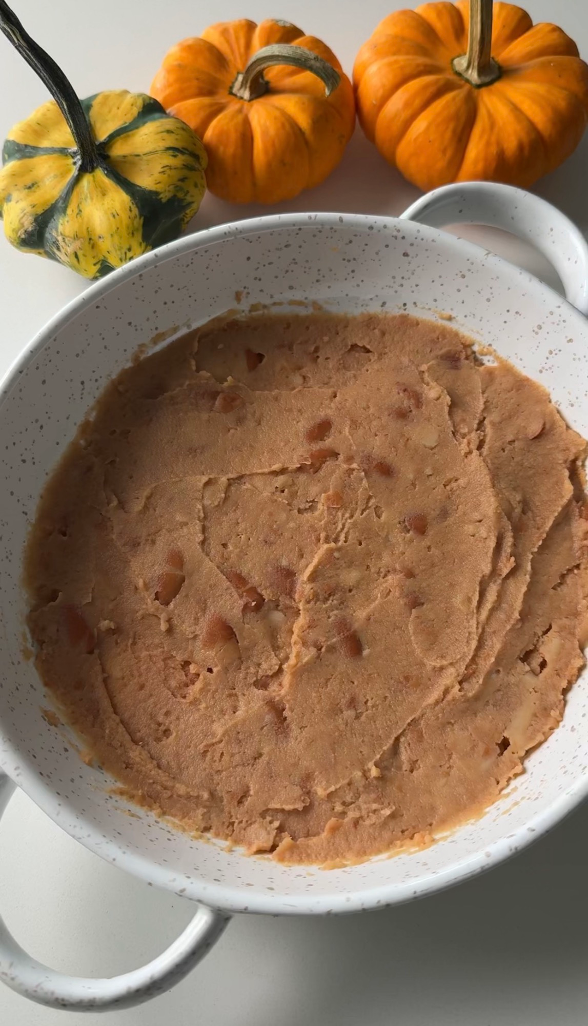 Refried beans spread in the bottom of a serving dish