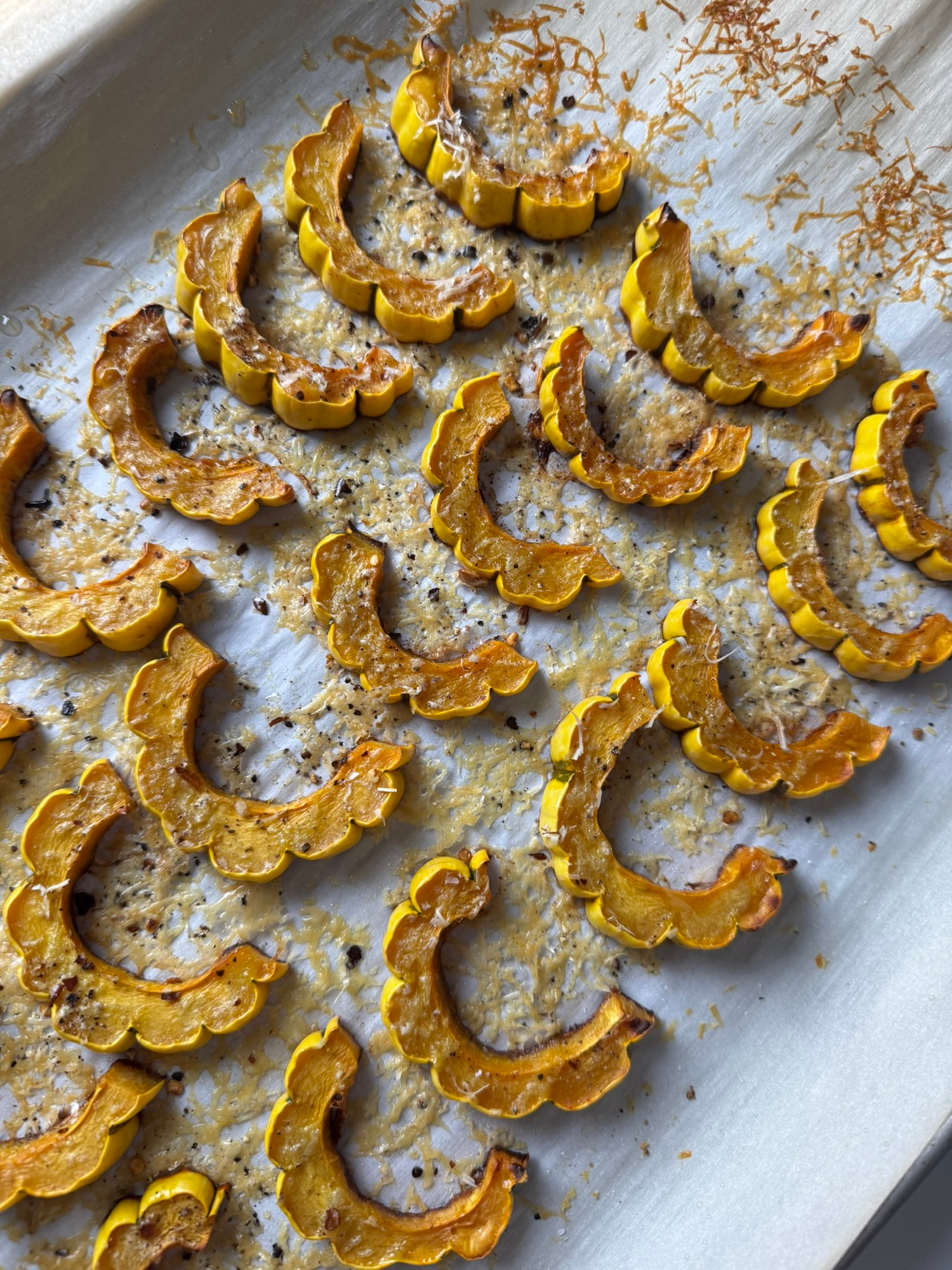 Roasted delicata squash slices on a parchment-lined baking sheet