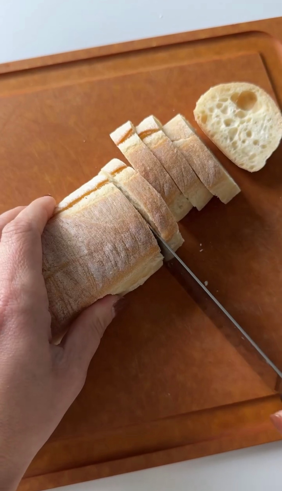 Slicing a baguette into rounds on a cutting board