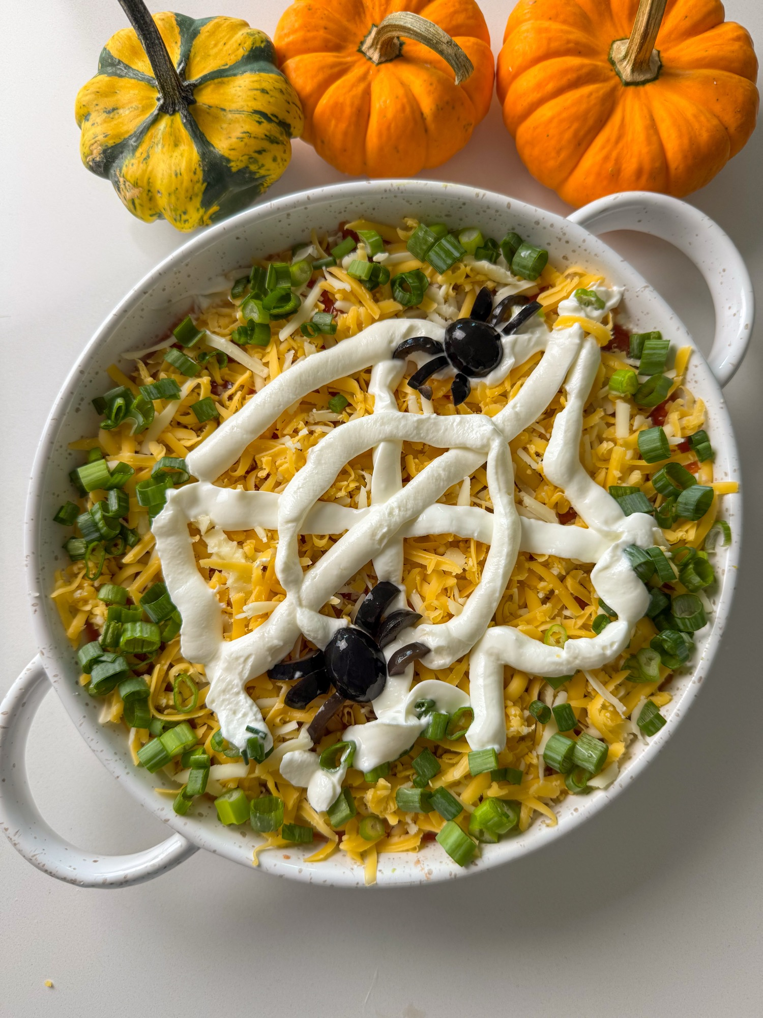 Spider web layered dip with a Greek yogurt web and olive spiders