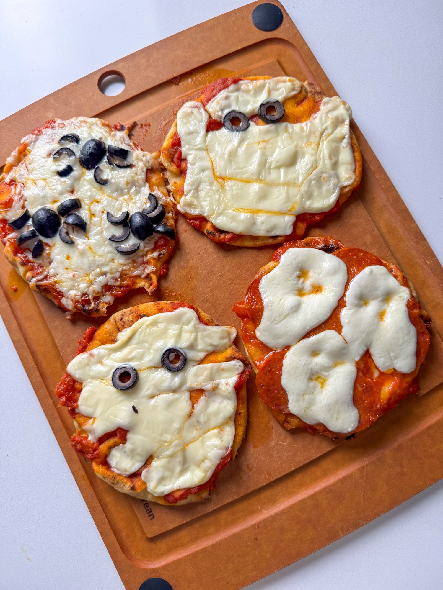 Baked spooky naan pizzas decorated as mummies, ghosts, and spiders