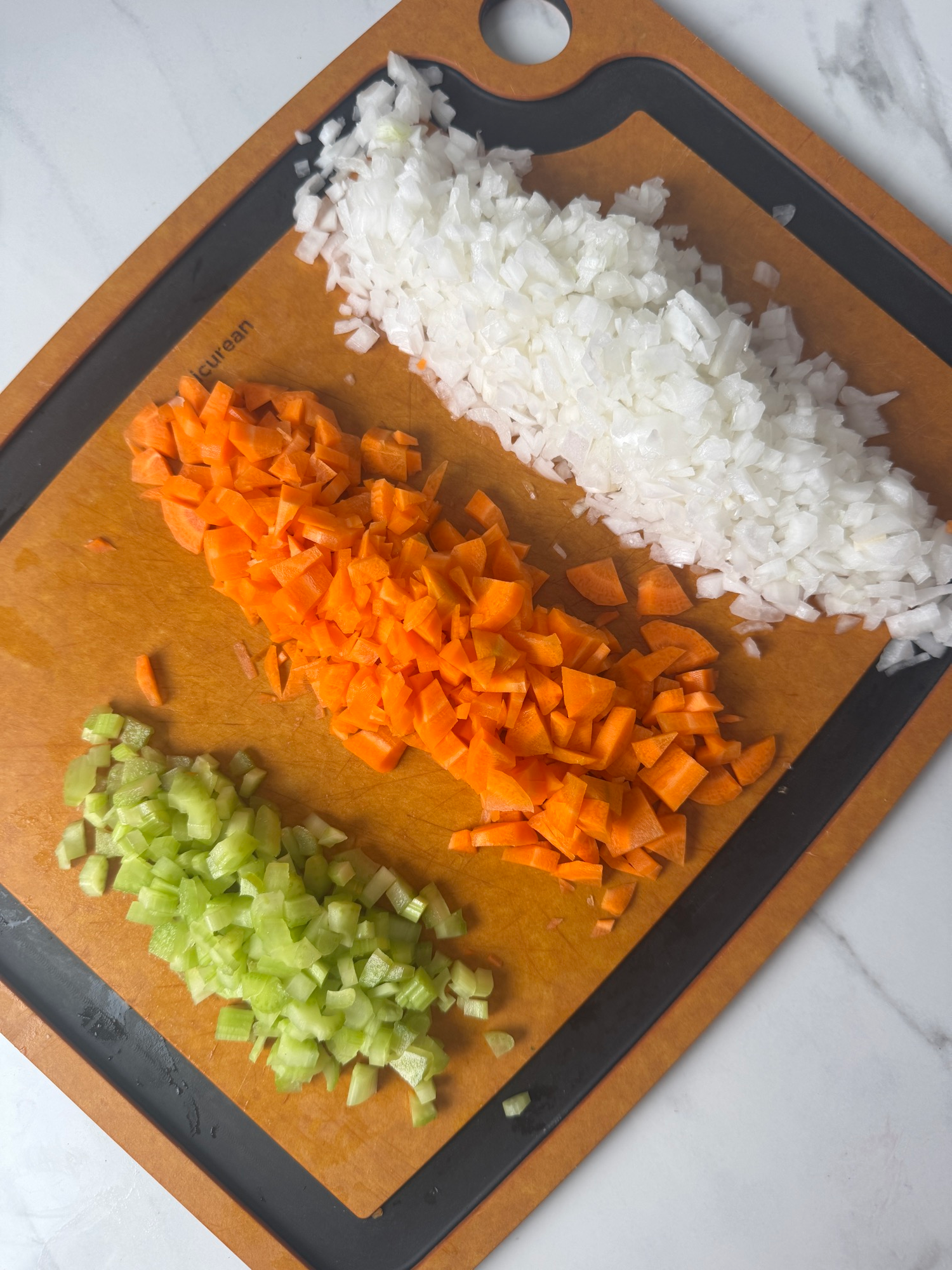 Diced onion, carrot, and celery on a cutting board for turkey pot pie pasta