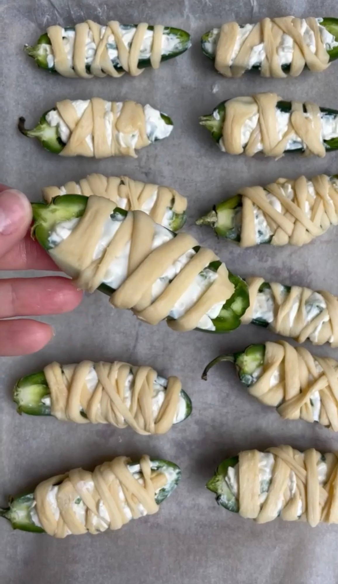 Jalapenos wrapped in crescent dough strips to look like mummies before baking